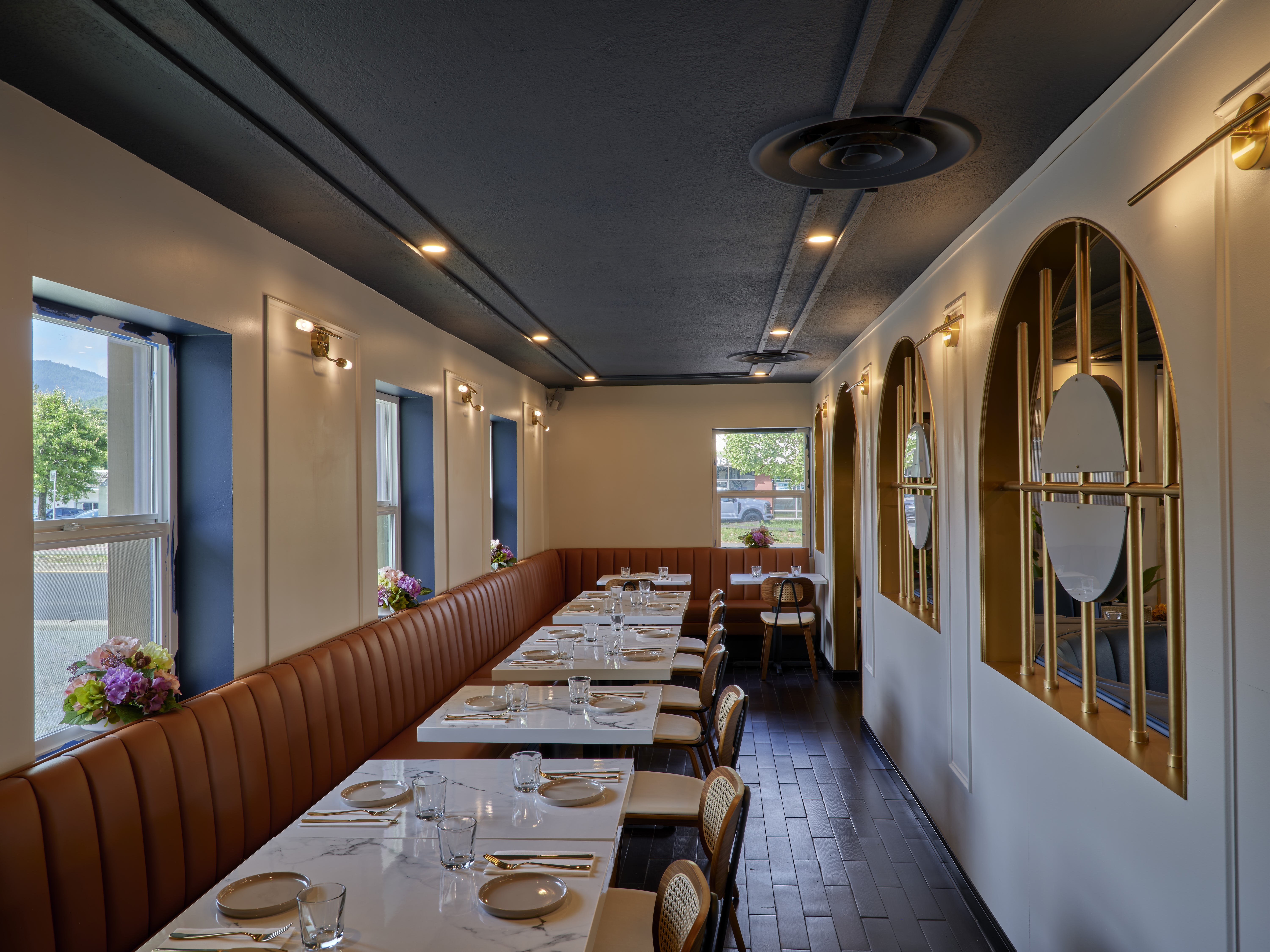 Warm leather booths and gold arch mirrors inside the Prettiplatters dining room in San Anselmo
