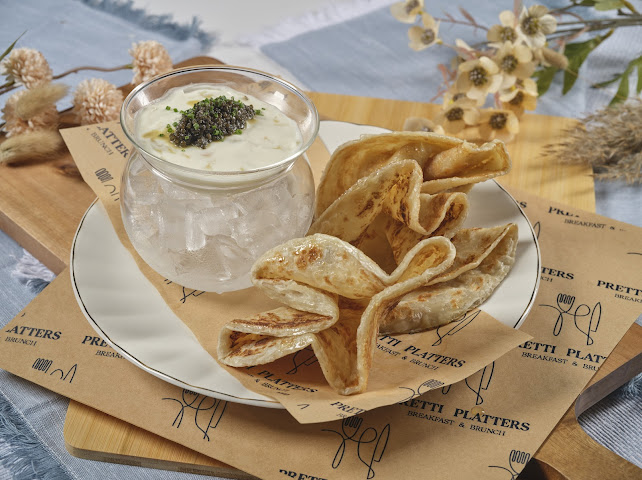 Kaluga Reserve caviar with crème fraîche in a glass bowl, served with crispy house roti at Prettiplatters
