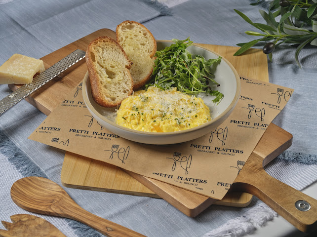 Morning Cheesy Scramble with soft Parmesan-crowned scrambled eggs, arugula, and sourdough toast at Prettiplatters