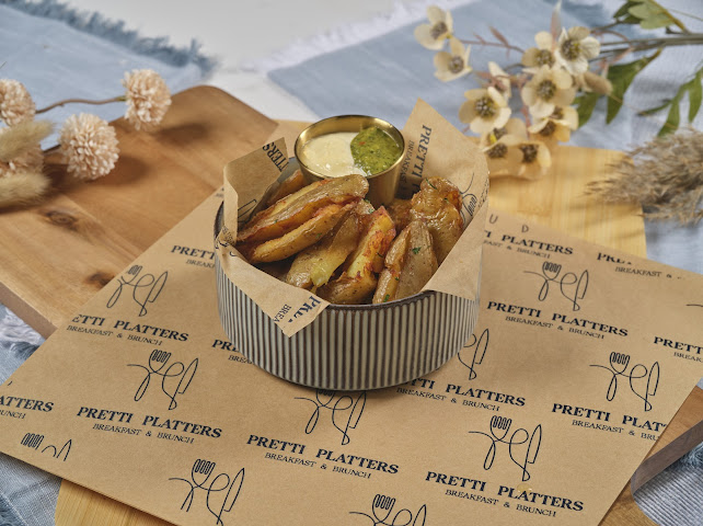 Golden smashed crispy potatoes in a basket with garlic aioli and salsa verde at Prettiplatters San Anselmo