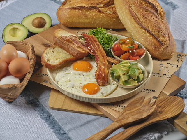The Pretti Breakfast — sunny side eggs, crispy bacon, avocado, cherry tomatoes, and sourdough toast at Prettiplatters